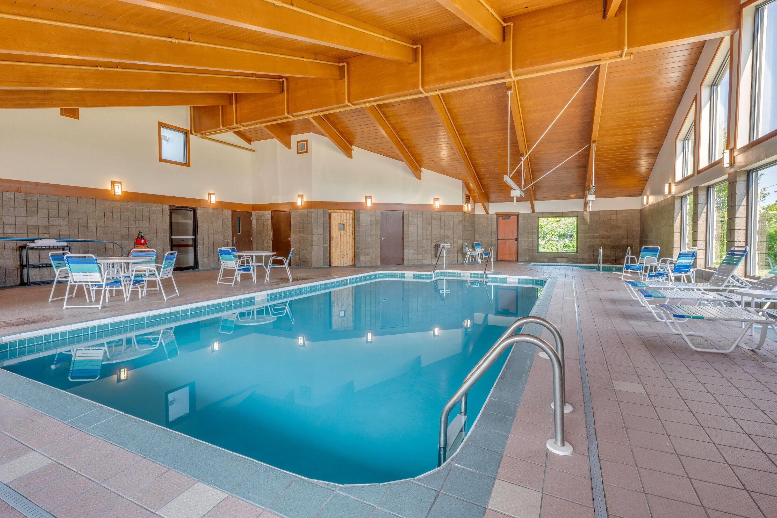 A large indoor swimming pool with multiple lanes, surrounded by lounge chairs and a covered seating area.