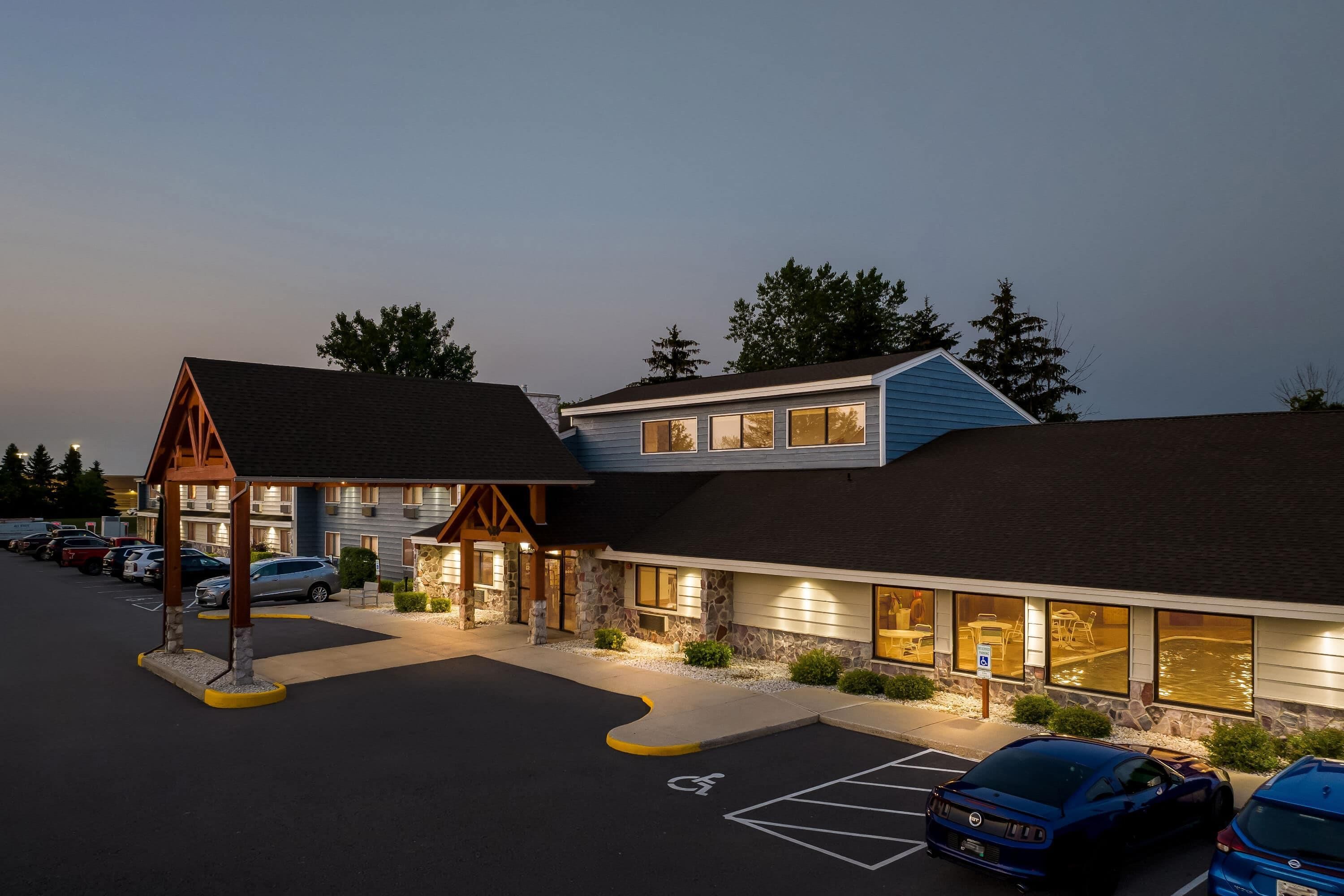 A hotel with a two-story structure, a covered outdoor area, and a parking lot with marked handicapped spaces.