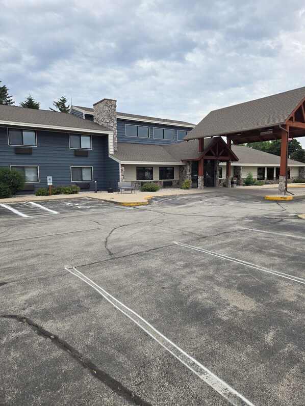 A building with a stone facade, multiple windows, and a covered entrance area. - AmericInn by Wyndham Sturgeon Bay (Sturgeon Bay)