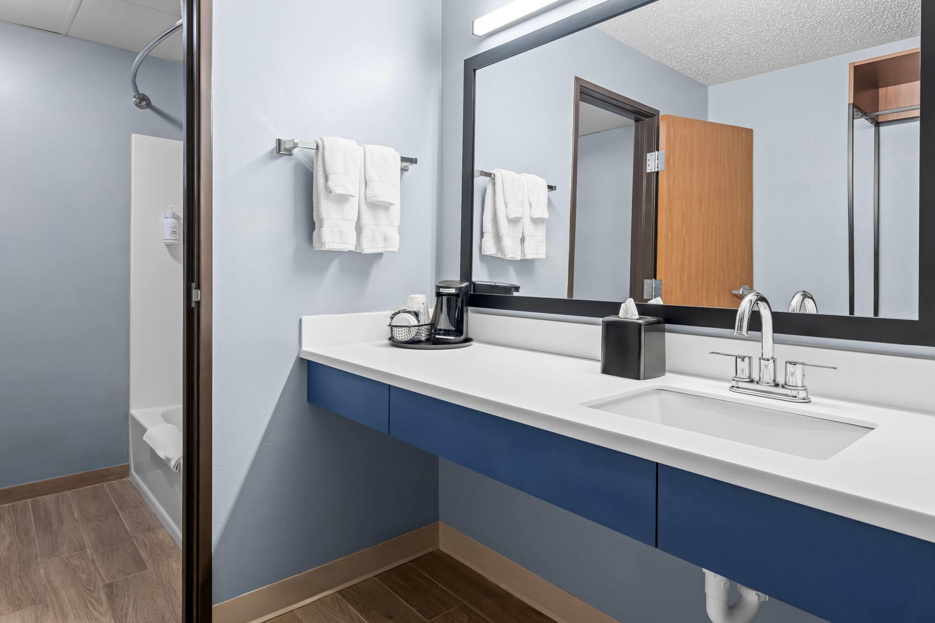 Une salle de bain moderne avec un lavabo blanc, un miroir et un porte-serviettes.