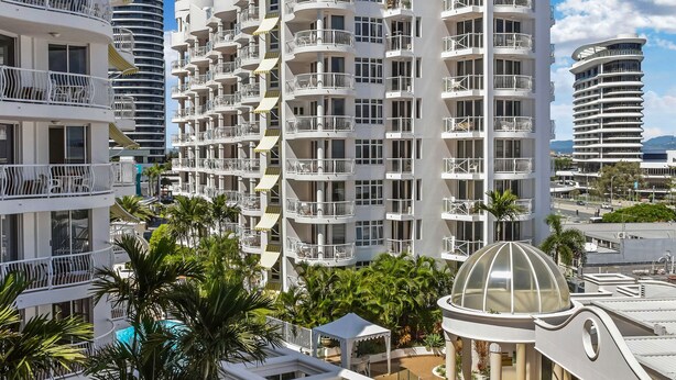 A resort with a pool, palm trees, and modern architecture. - Phoenician Resort (Broadbeach)