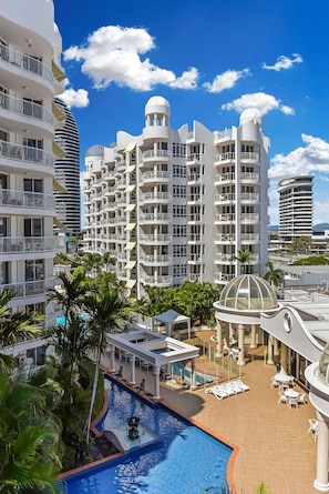 Un resort con piscina, palmeras y arquitectura moderna.