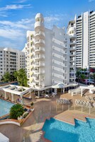 Un hotel con varios balcones, piscina y bar en la azotea.