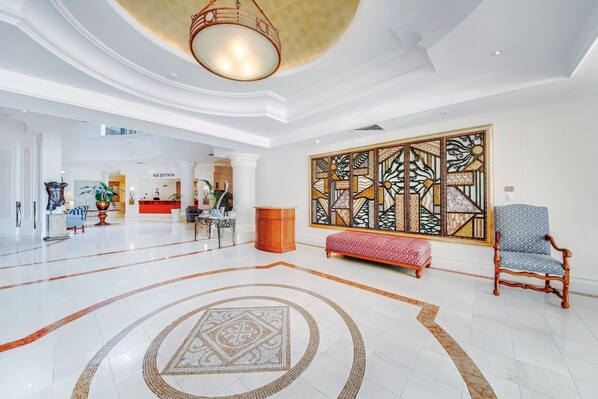 A spacious lobby with a reception desk, a large decorative wall, and a seating area with a patterned rug. - Phoenician Resort (Broadbeach)
