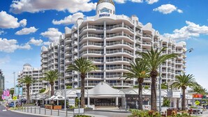 A multi-story hotel with a distinctive dome-shaped top, balconies, and palm trees in the foreground. - Phoenician Resort (Broadbeach)