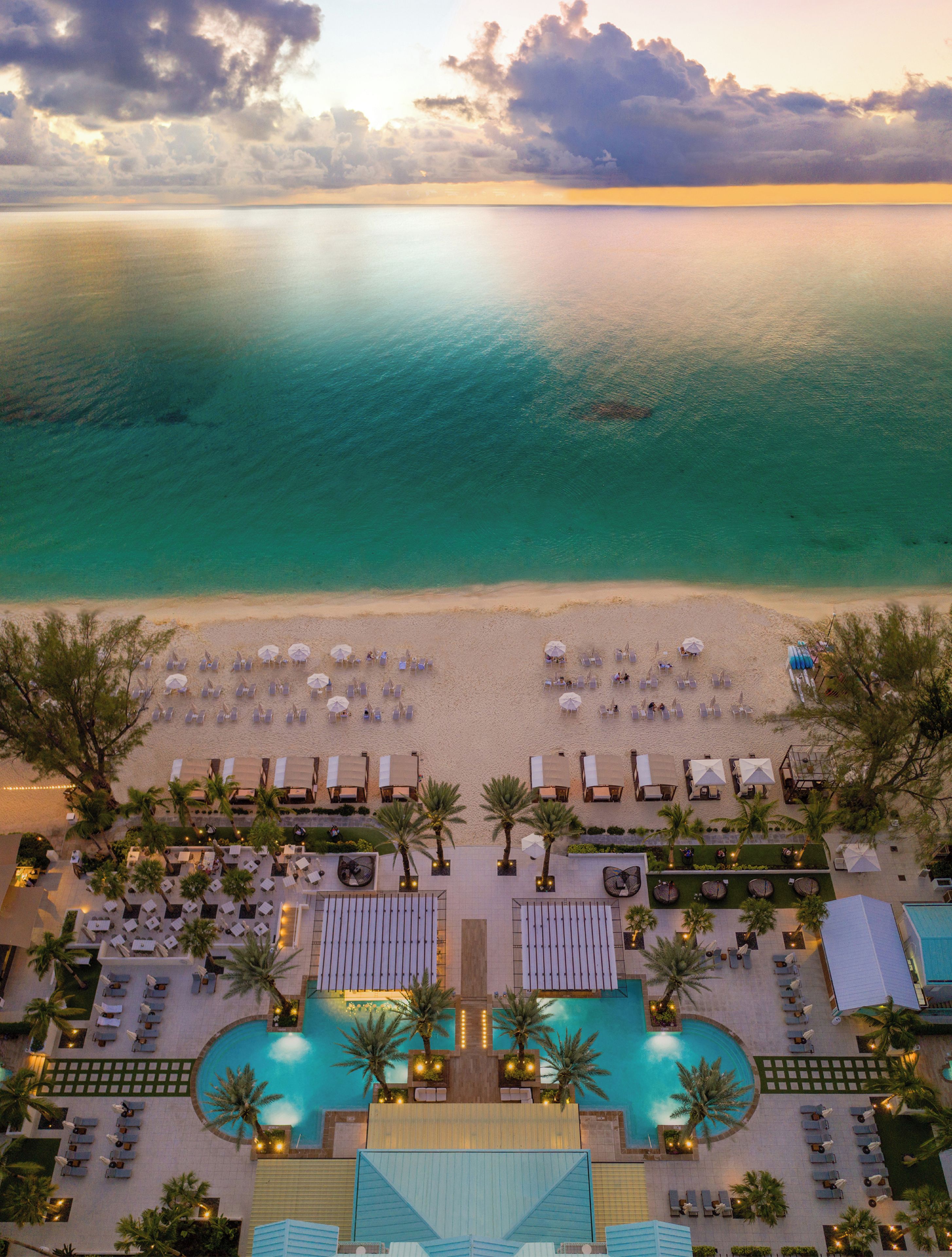 A resort with a pool, beach area, and lounge chairs.