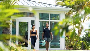 A modern house with large glass windows, a white exterior, and a well-maintained lawn. - The Sunshine Hotel and Suites (Seven Mile Beach)
