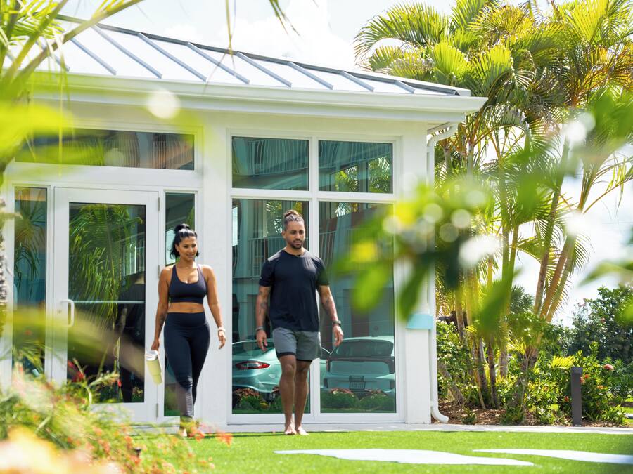 A modern house with large glass windows, a white exterior, and a well-maintained lawn.