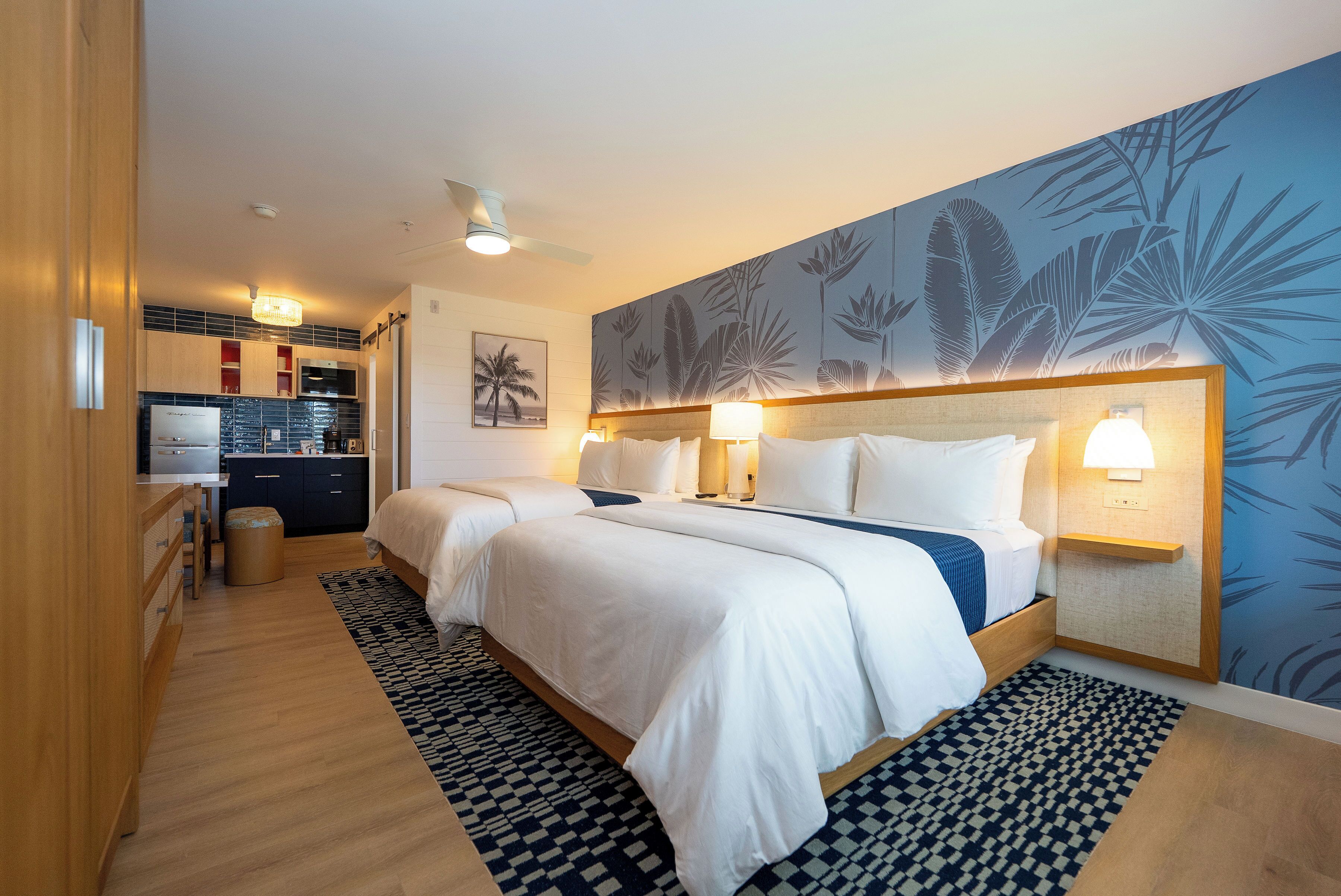 Una habitación de hotel con una cama grande, un escritorio y una kitchenette.