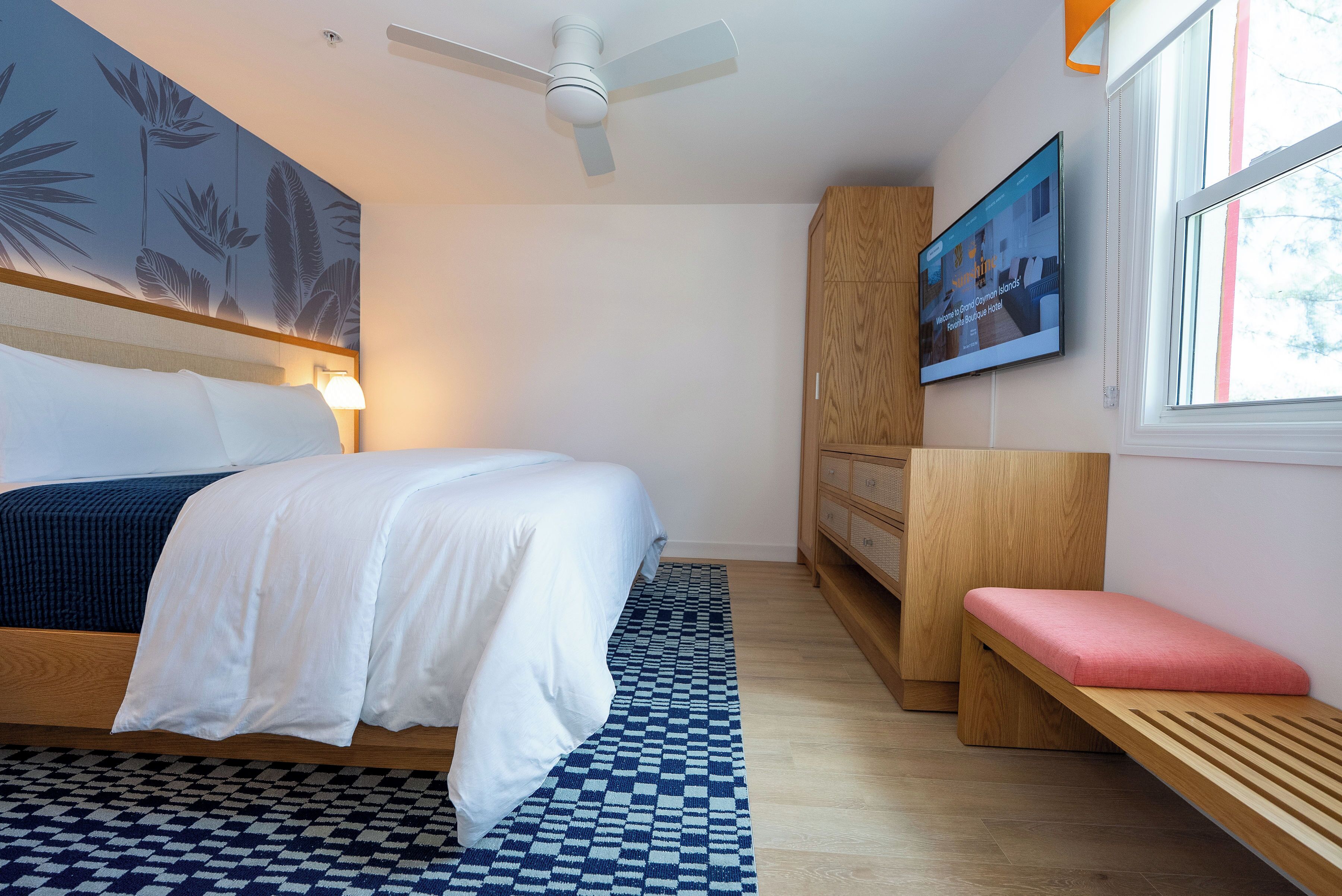 Una habitación de hotel con cama, escritorio, silla, ventilador de techo y ventana.