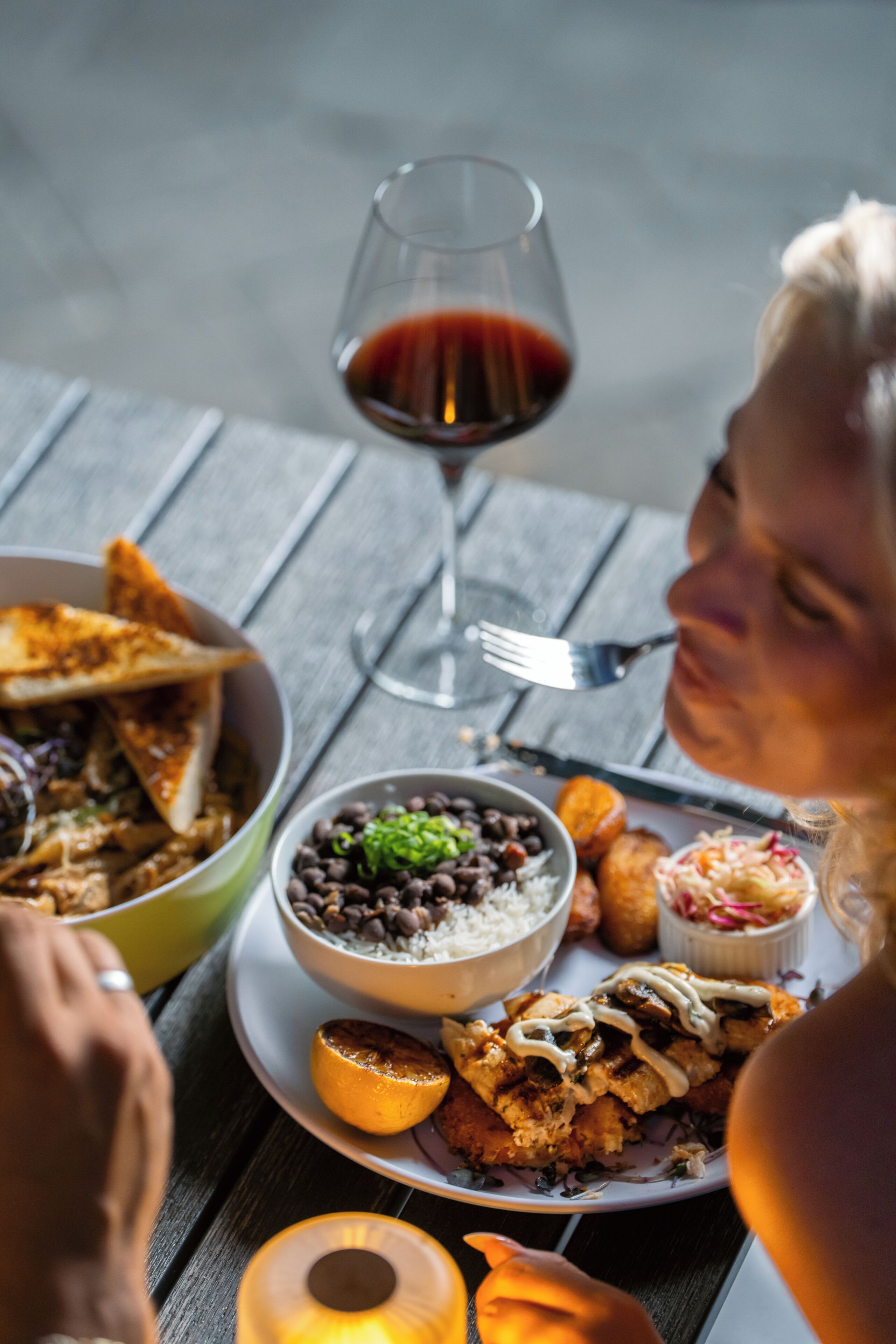 Un tavolo da pranzo imbandito con diversi piatti, un bicchiere di vino rosso e una candela.