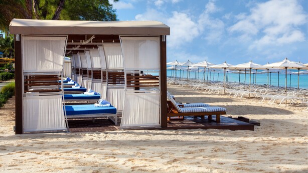 A beachside resort with multiple sun loungers and a covered seating area. - The Sunshine Hotel and Suites (Seven Mile Beach)