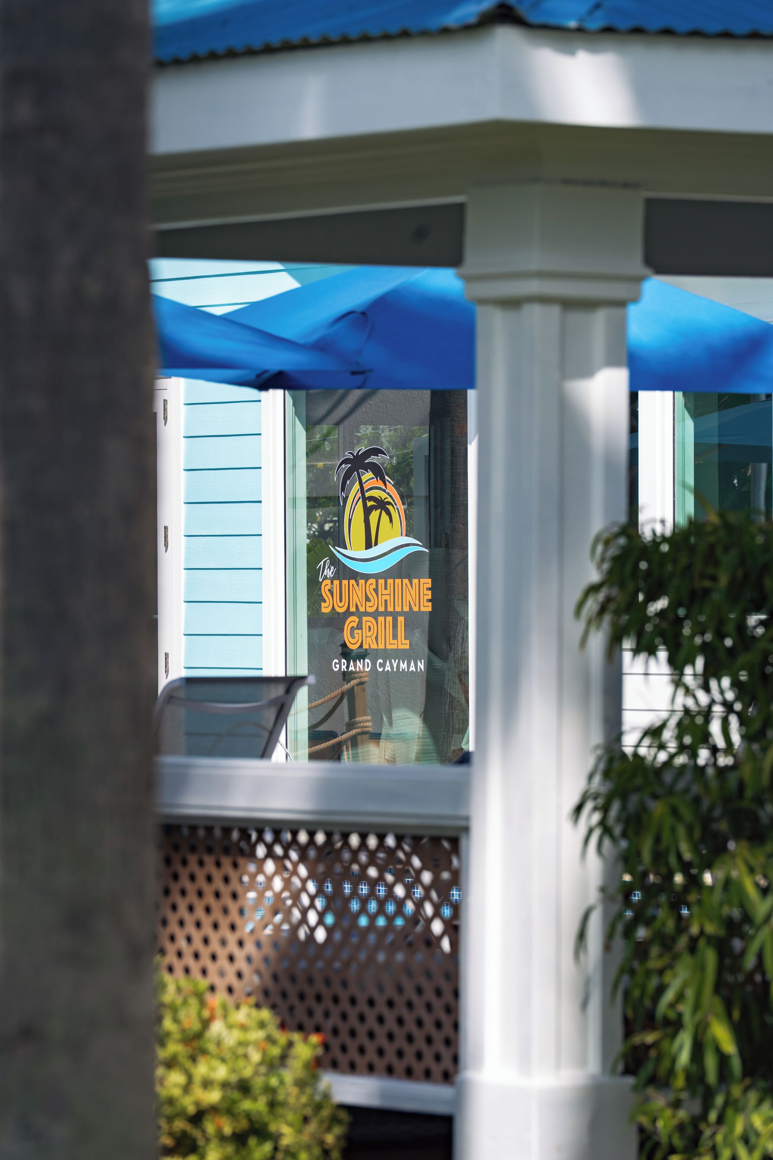 Letrero de restaurante con logotipo de palmera y el nombre 'Sunshine Grill' en un edificio.