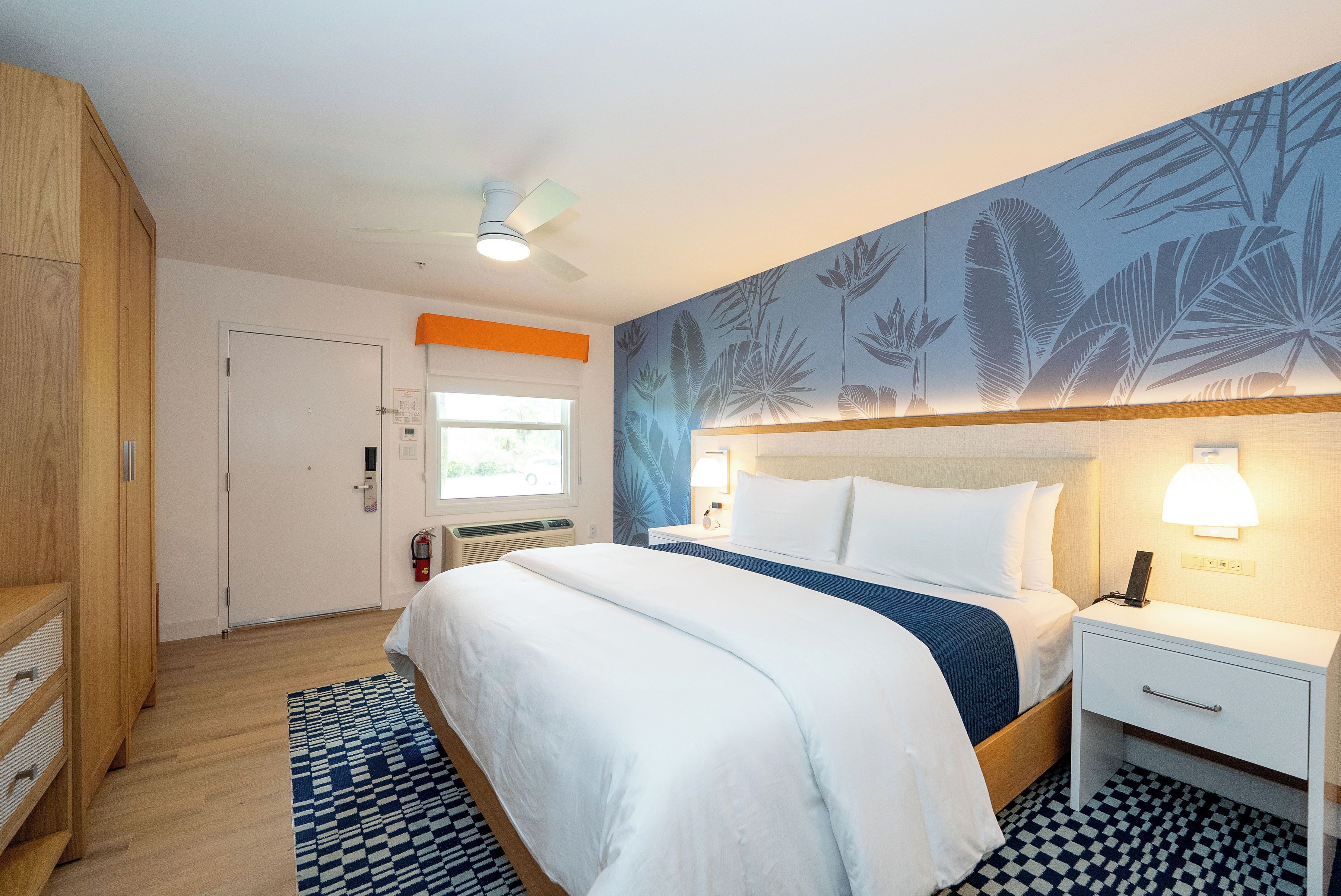 Una habitación de hotel con cama, mesita de noche y ventana.