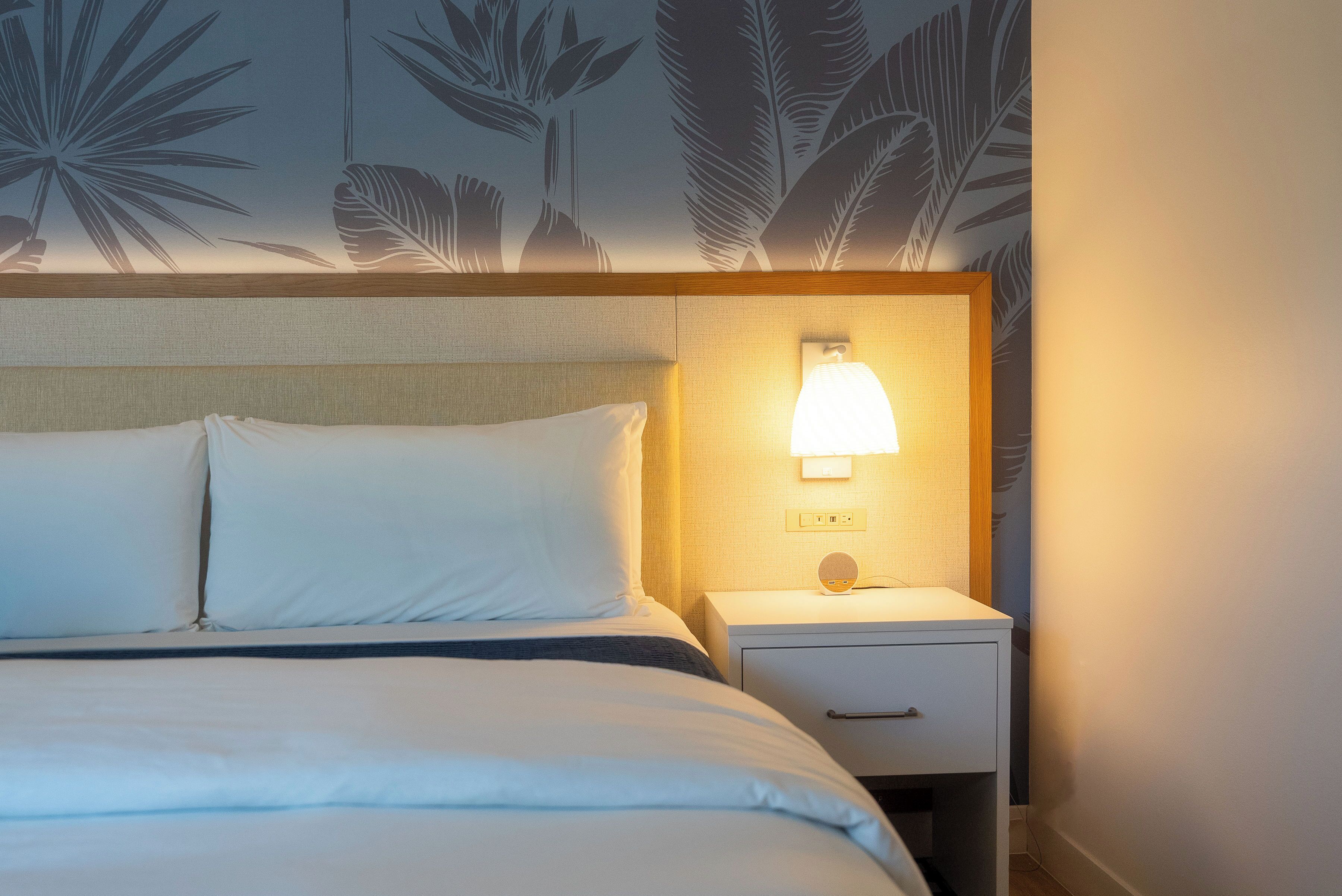 Ein Hotelzimmer mit Bett, Nachttisch und Wandlampe.