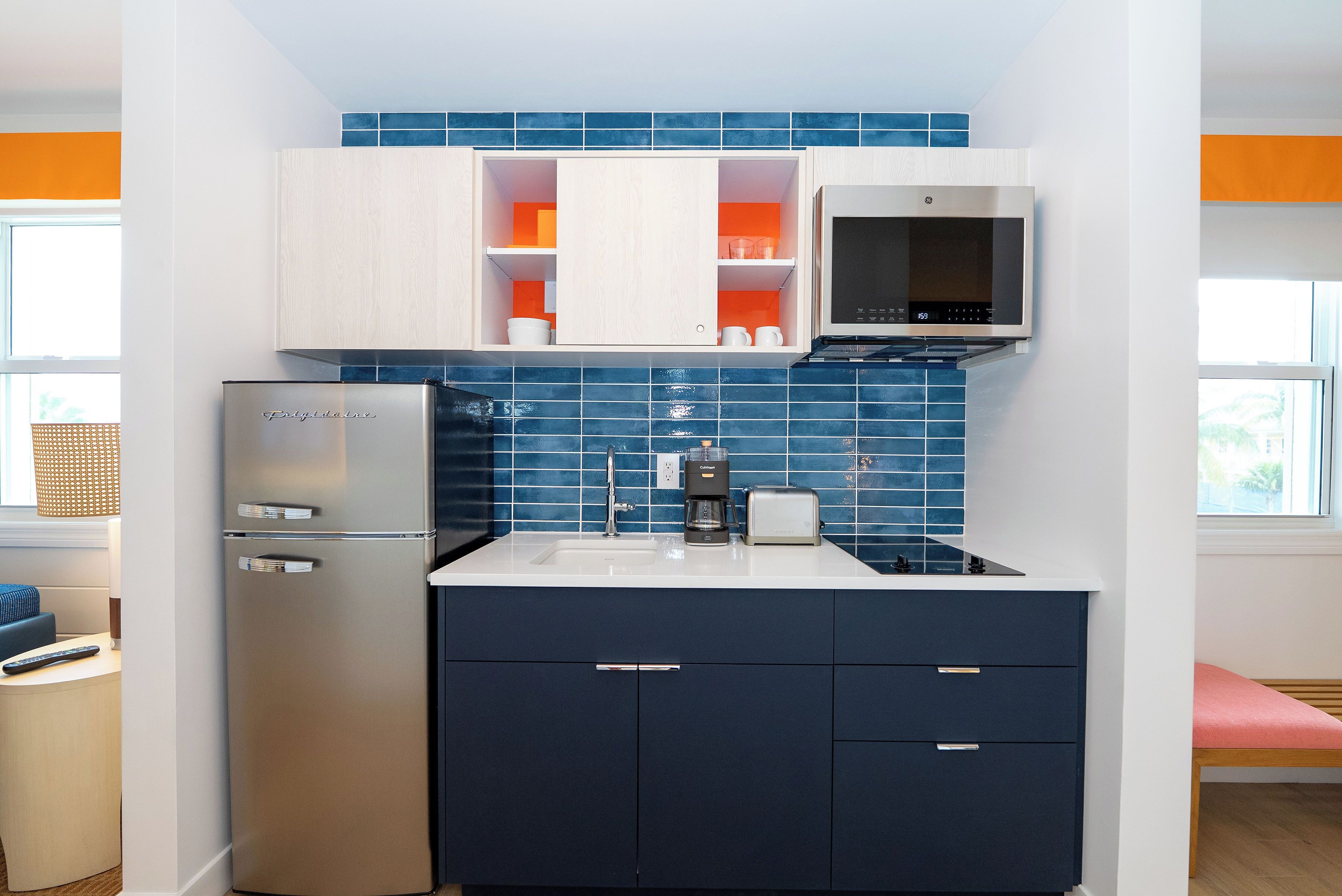 A compact kitchen with a built-in refrigerator, a coffee maker, and a toaster.