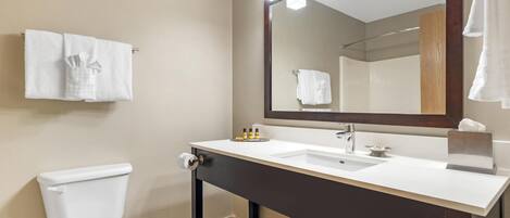 A modern bathroom with a white toilet, a dark vanity with a mirror, and a white sink.