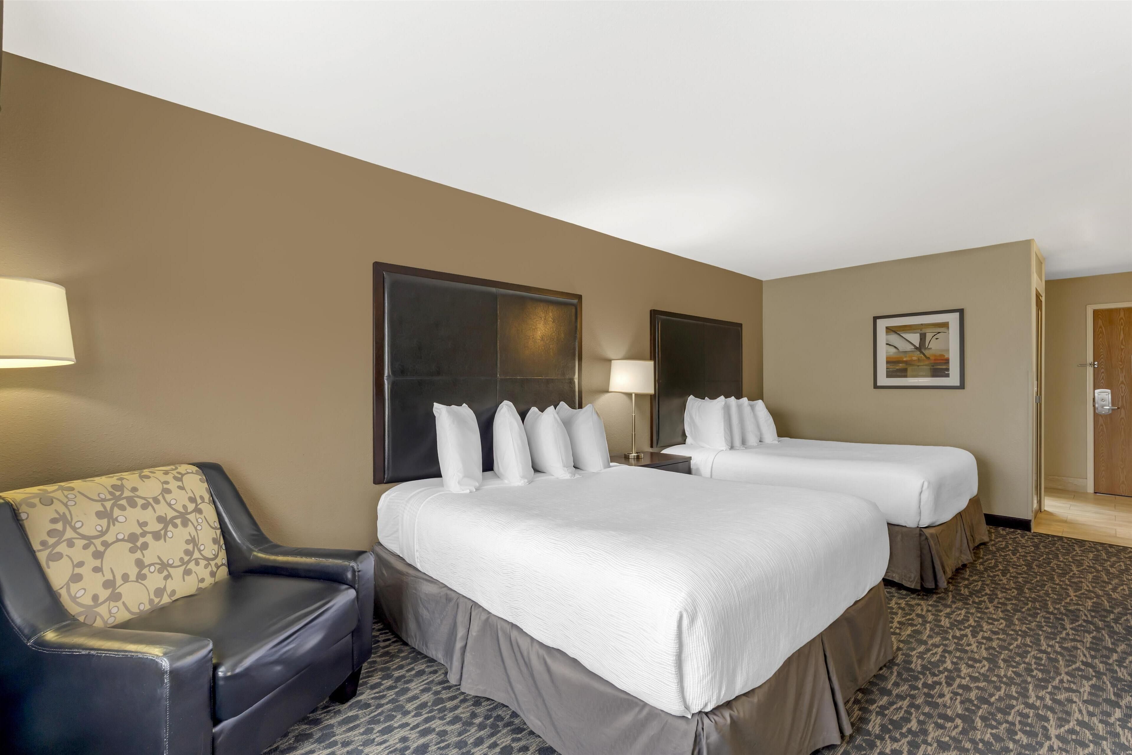 A hotel room with two beds, a sofa, and a large mirror.