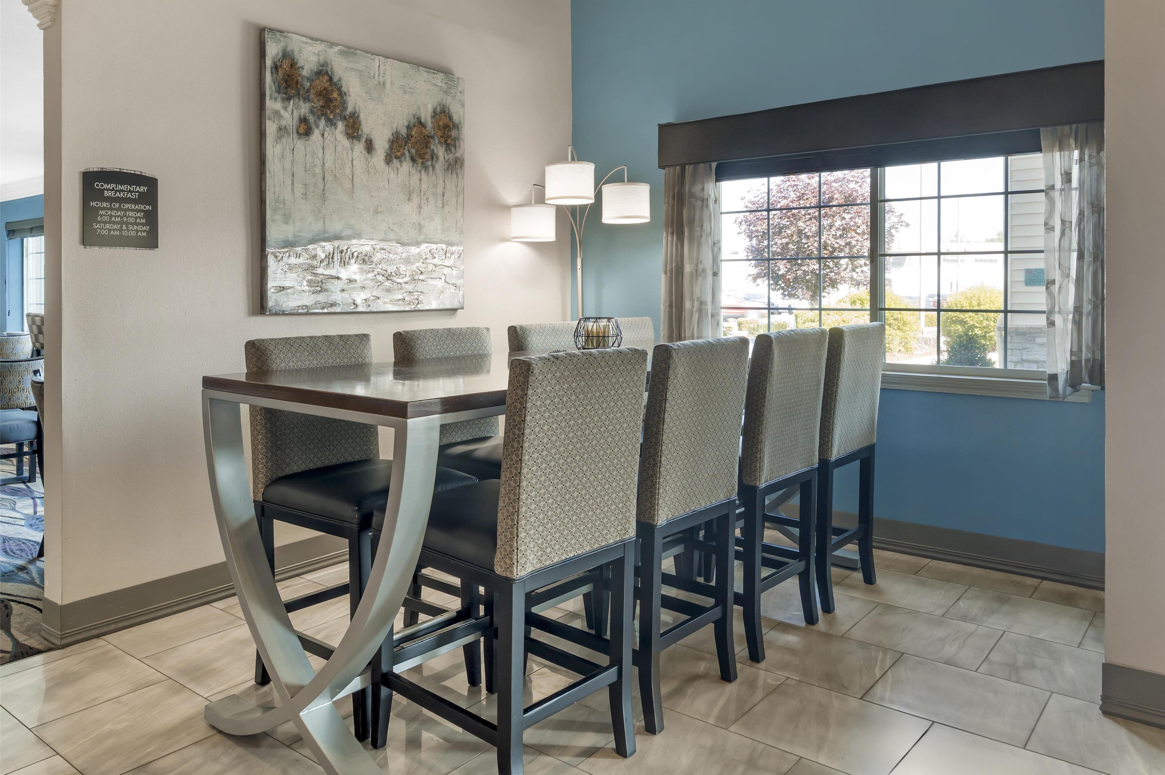 Un coin repas avec une table et des chaises modernes, un tableau au mur et une fenêtre donnant sur un beau paysage.