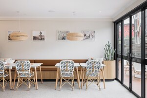 Un comedor moderno con sillas de mimbre, un banco de madera y lámparas colgantes de ratán.