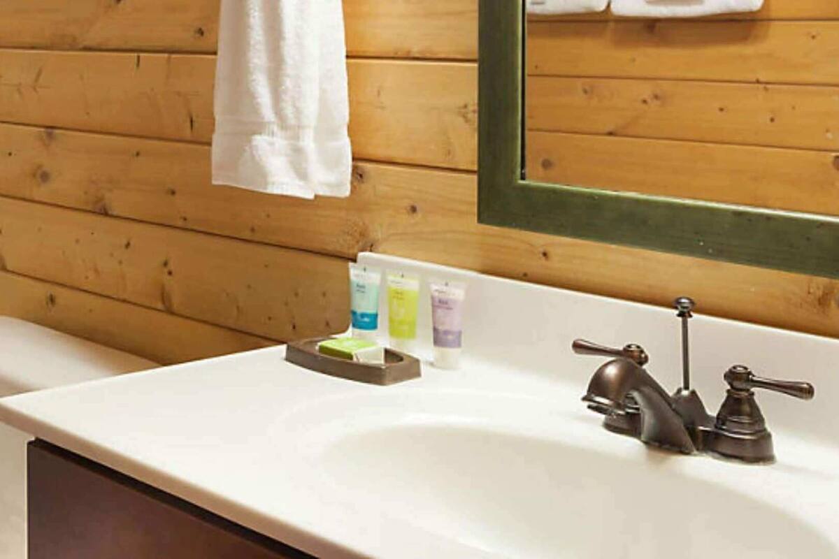Une salle de bain avec un mur en bois, un lavabo blanc et un miroir.