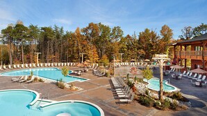 Un complexe hôtelier doté de plusieurs piscines, d’espaces de détente et d’un bâtiment en bois avec un balcon.