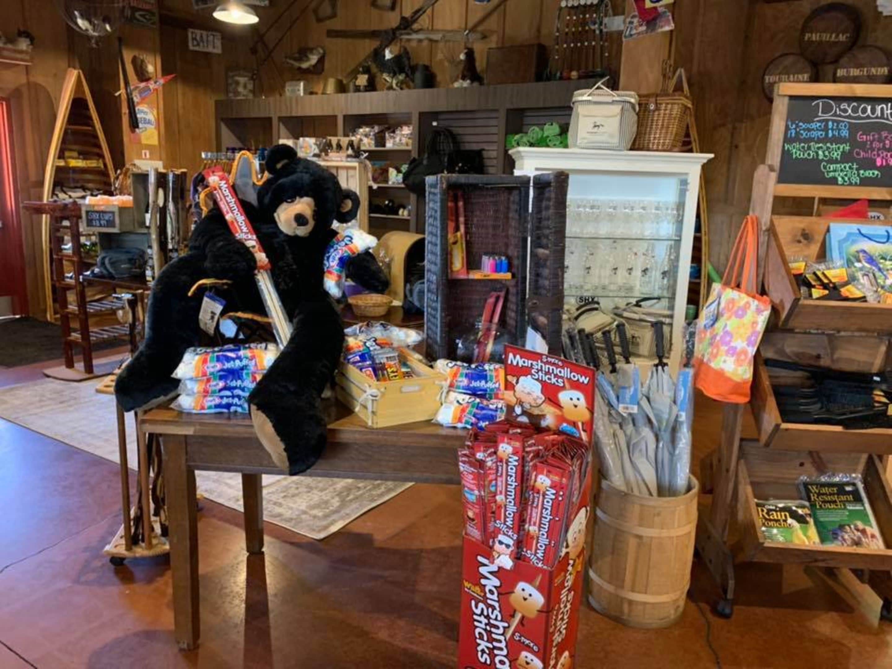 A store with a large black bear mascot, various packaged goods, and a chalkboard sign advertising discounts.