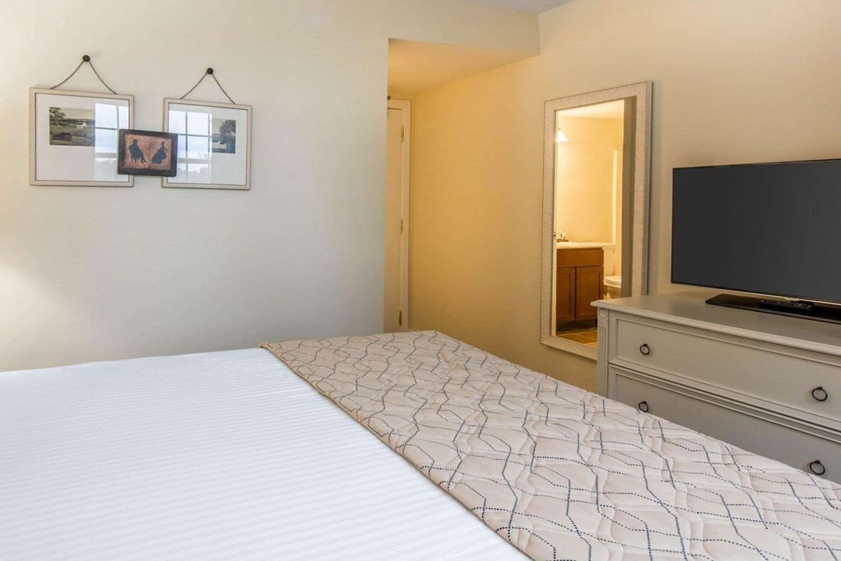 Une chambre d’hôtel avec un lit, une commode, un téléviseur et deux tableaux encadrés au mur.