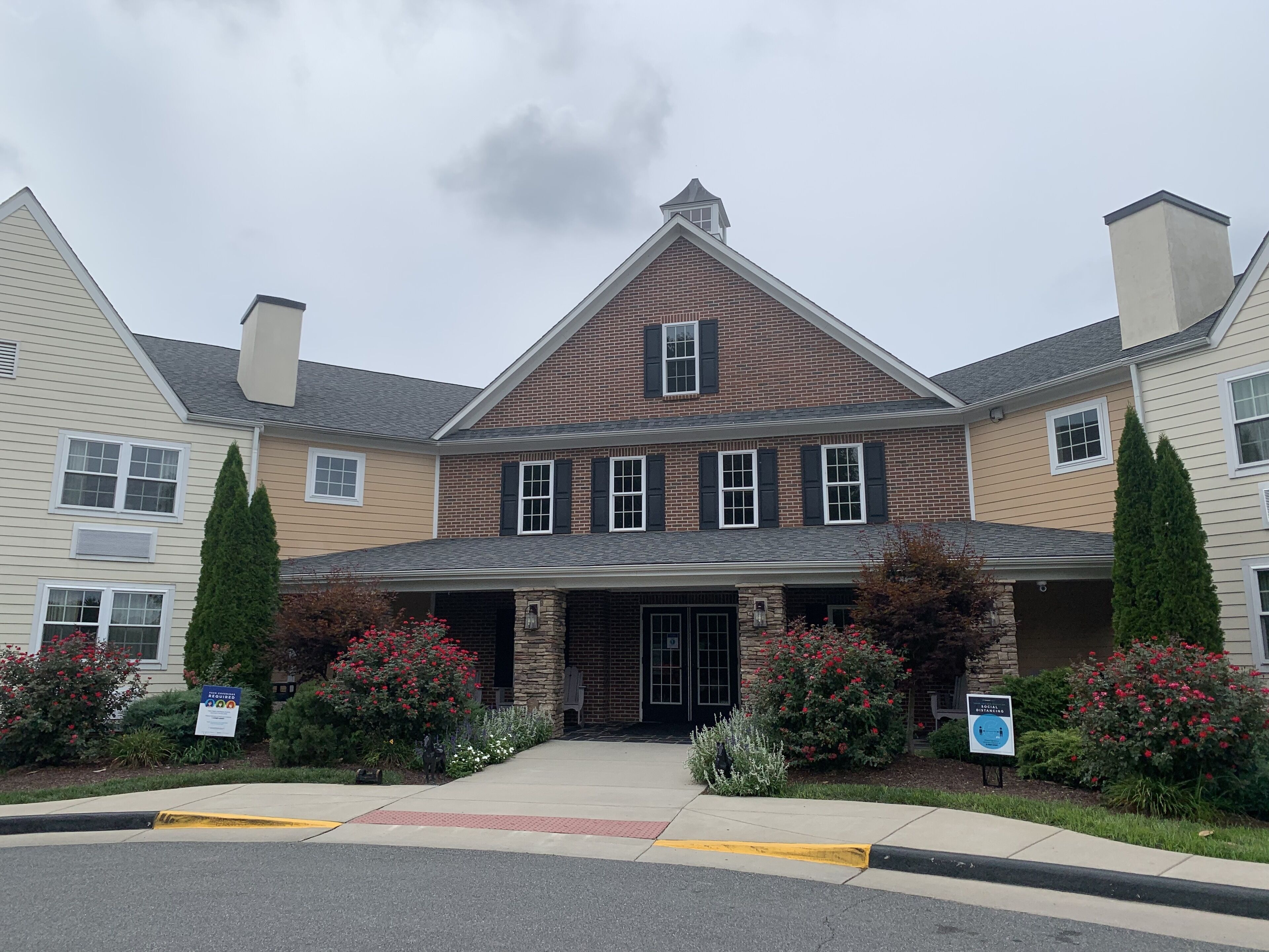 A two-story building with a brick facade, a stone entrance, and a covered front porch.