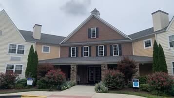 A two-story building with a brick facade, a stone entrance, and a covered front porch.