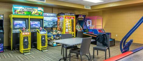 Une salle d’arcade intérieure proposant divers jeux, notamment « Time Crisis 3 » et « Movie Stop », ainsi qu’une table de ping-pong.