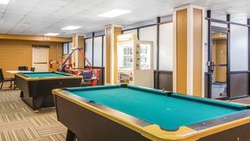 Enjoy games and relaxation in this spacious room with pool tables, chairs, and a table.