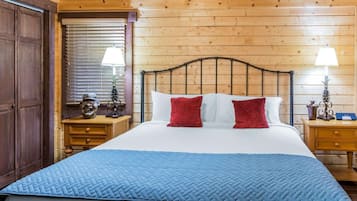 Una habitación con paneles de madera, una cama, dos mesitas de noche y una ventana con persianas.