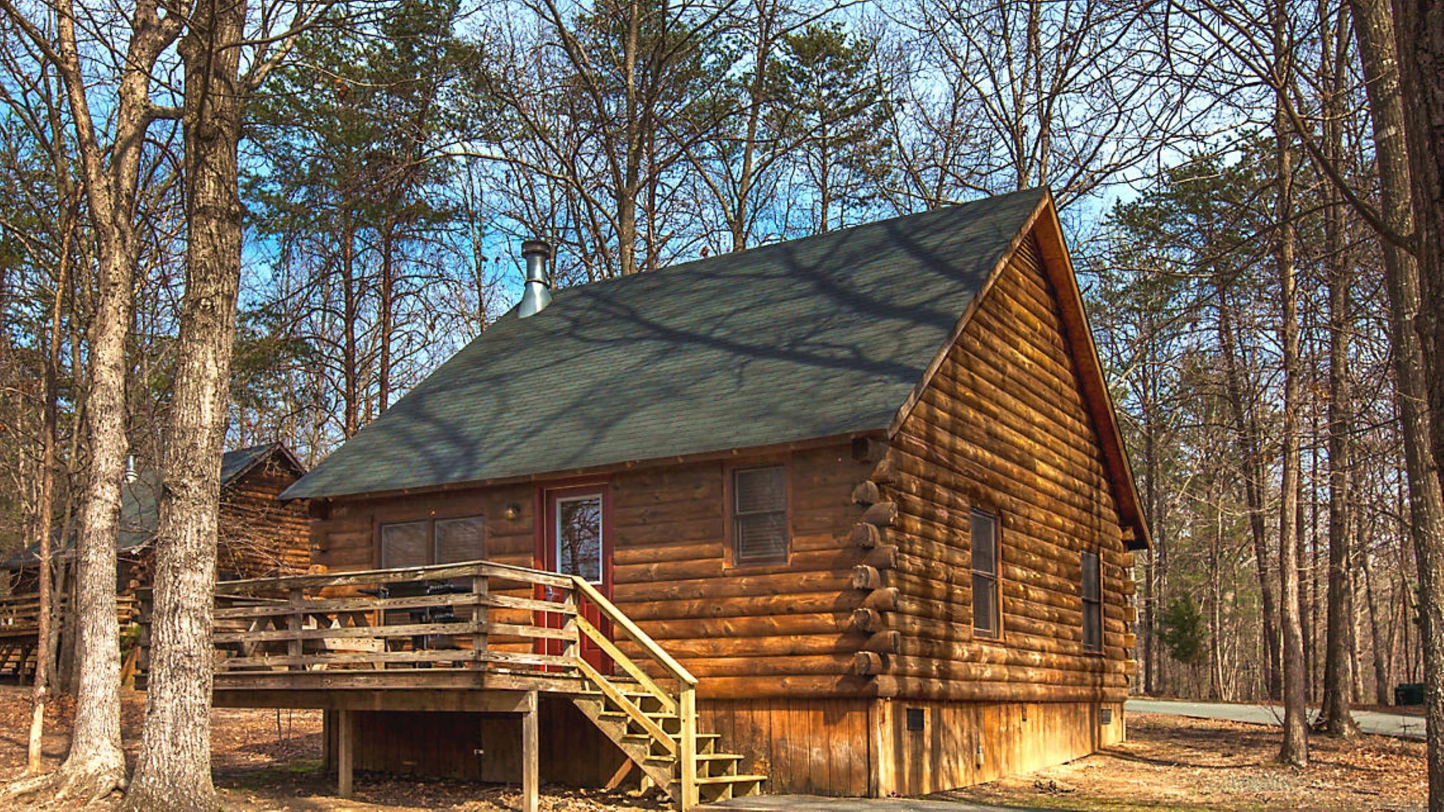 A log cabin with a staircase leading up to the entrance, surrounded by trees.