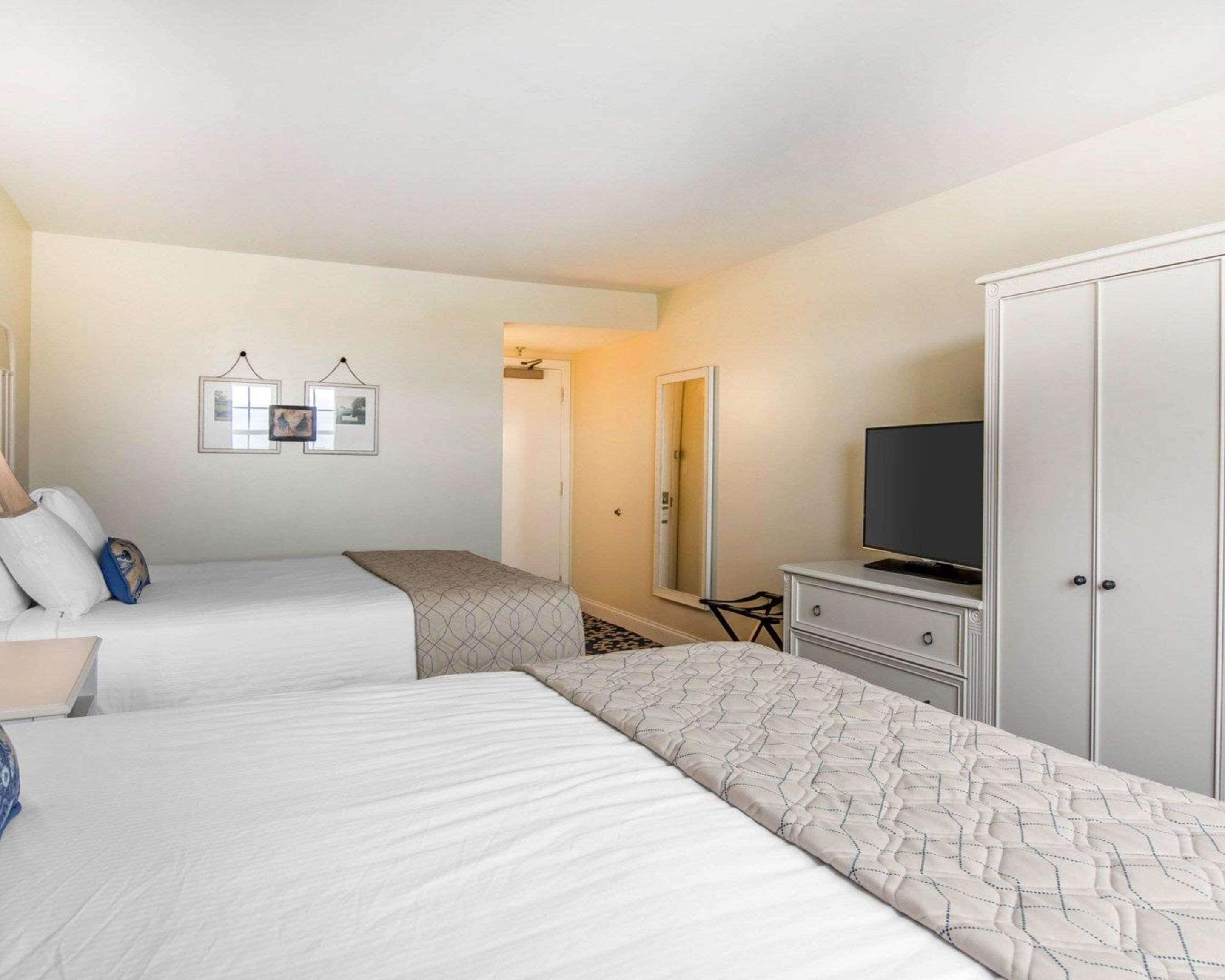 Ett hotellrum med två sängar, en tv, en garderob och en spegel.