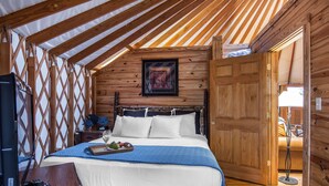 Un intérieur en bois avec un lit, un téléviseur et une porte en bois.