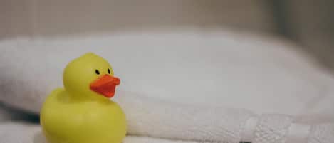 Un patito de goma amarillo sobre una toalla blanca.