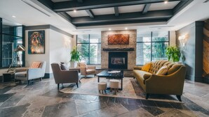 Un amplio salón con chimenea, muebles modernos y ventanas grandes.