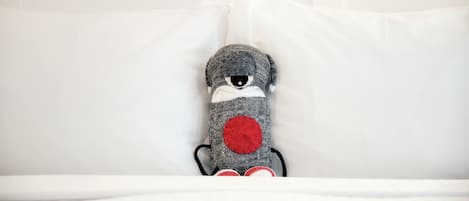 Un peluche sobre una cama blanca con almohadas.