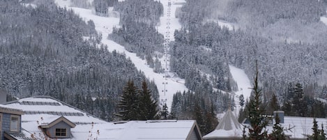 A residential area with snow-covered houses and a ski slope in the background.