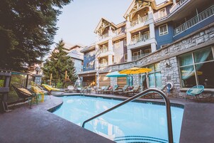 Una piscina al aire libre, sombrillas, sillones reclinables de piscina
