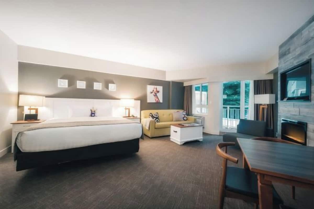 Een moderne hotelkamer met een bed, een bank, een eettafel en een televisie.