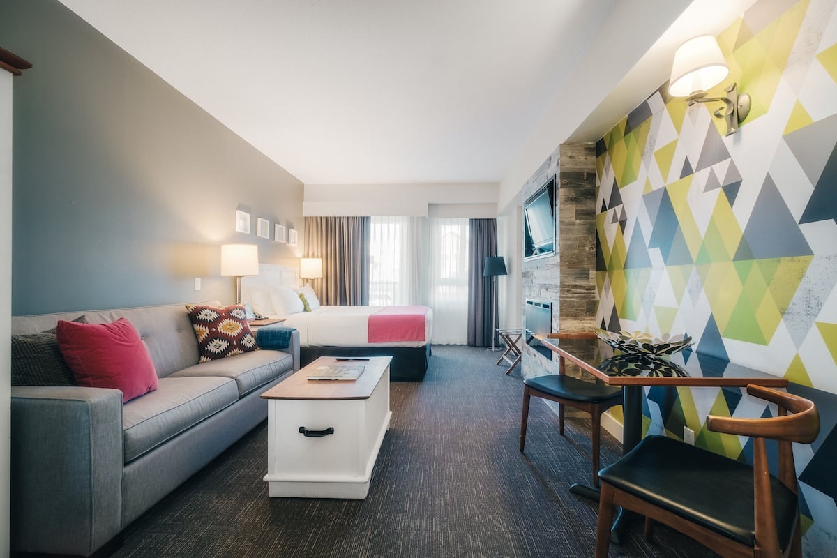 Een hotelkamer met een bank, een bed, een bureau en een stoel.