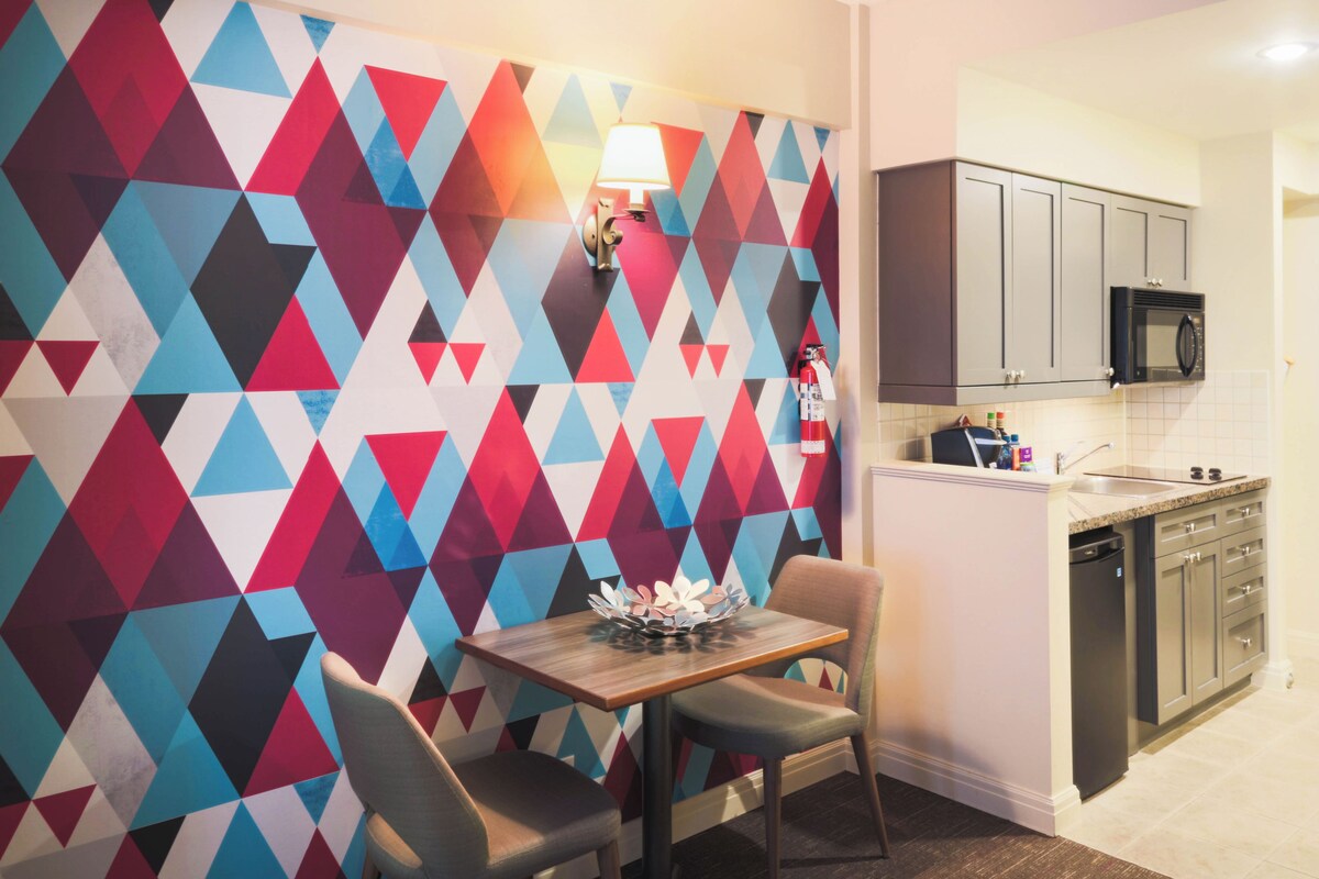 A modern kitchen with a microwave, cabinets, and a dining area with a table and chairs.