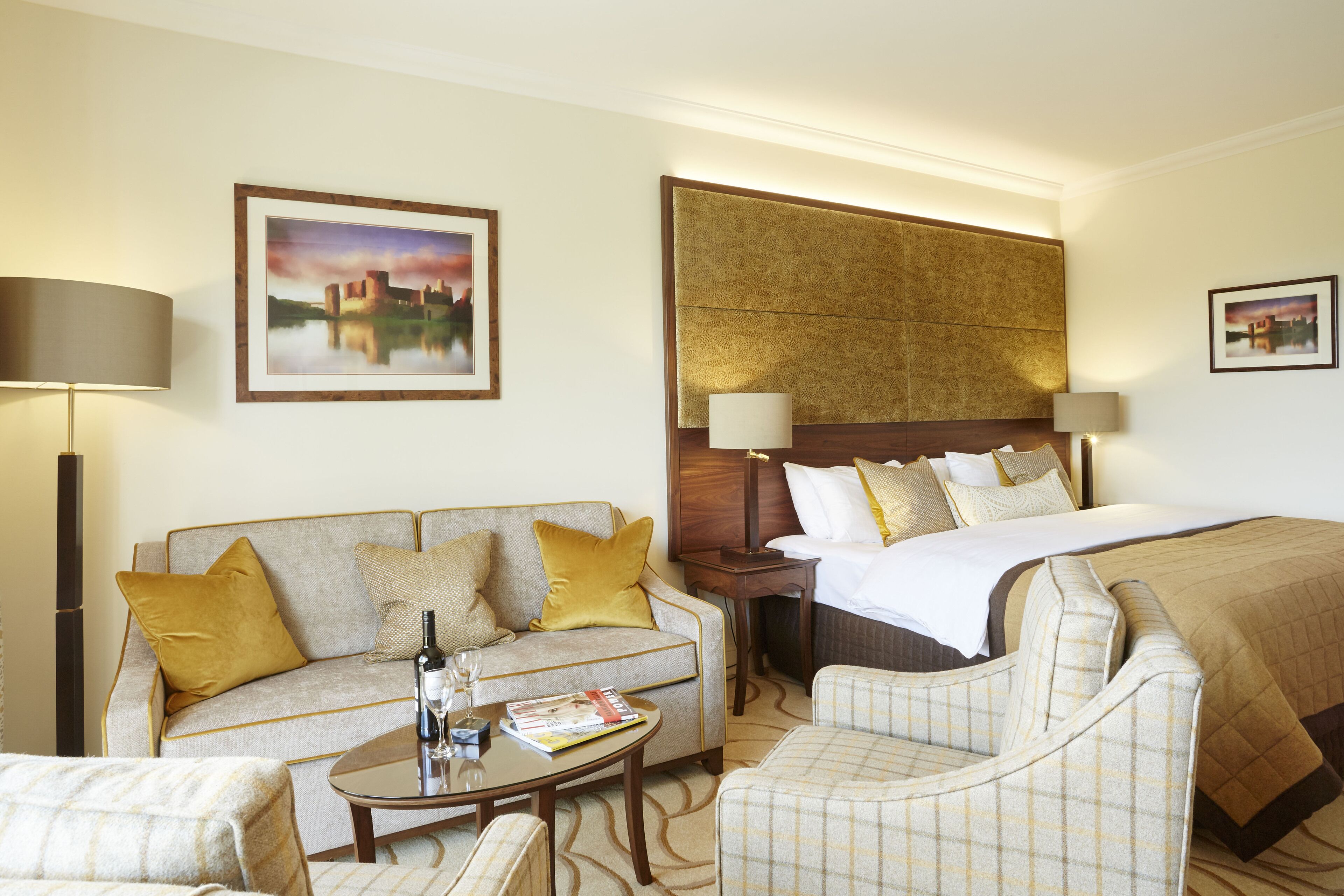 A hotel room with a bed, a sofa, a coffee table, and a chair.