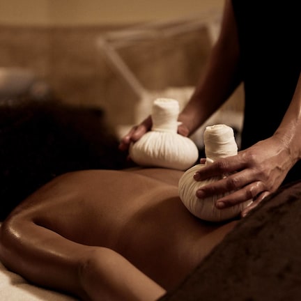 A massage therapy session in a dimly lit room with a candle on a table.