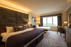 A hotel room with two beds, a desk, and a chair.