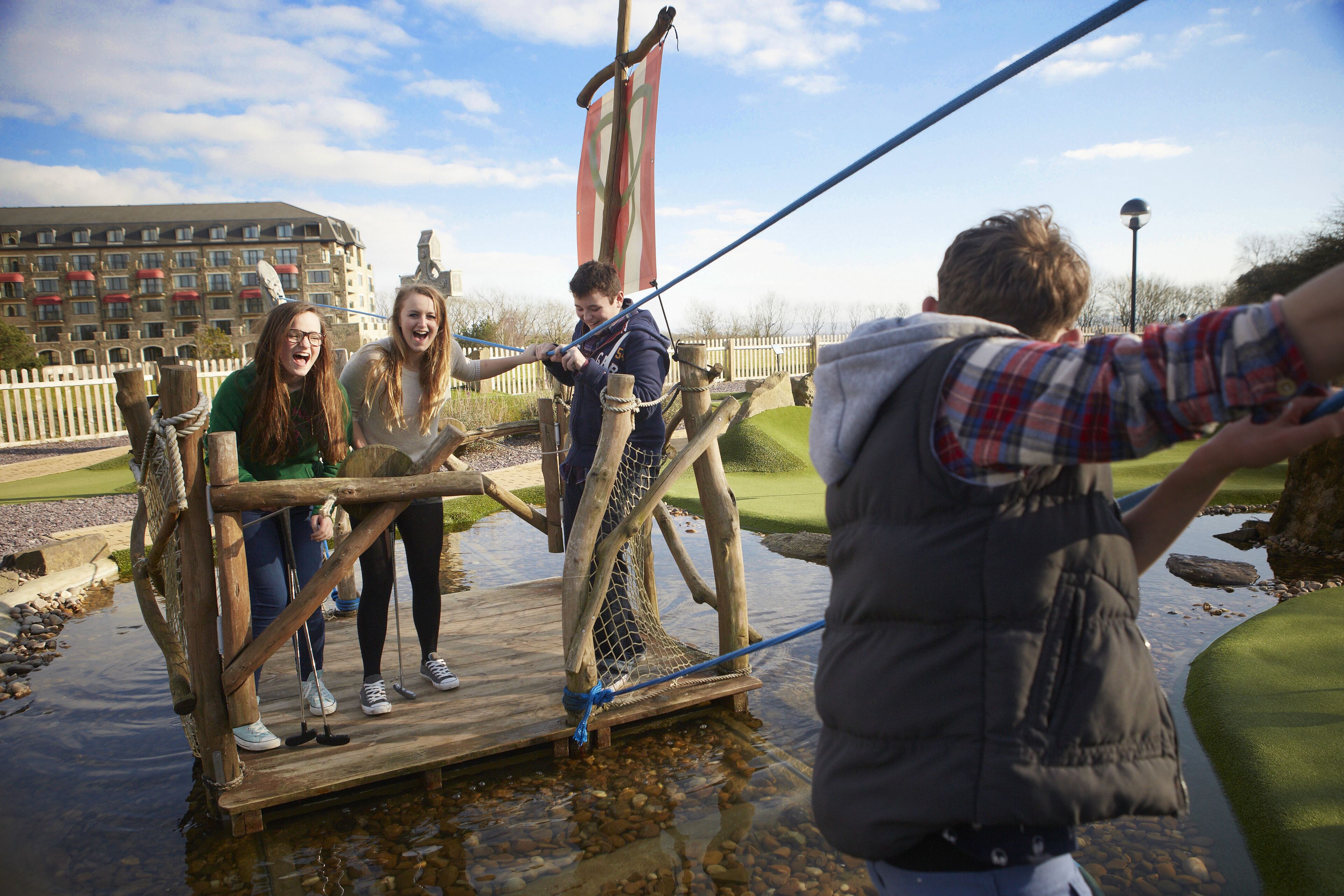 A wooden bridge over water with people standing on it.