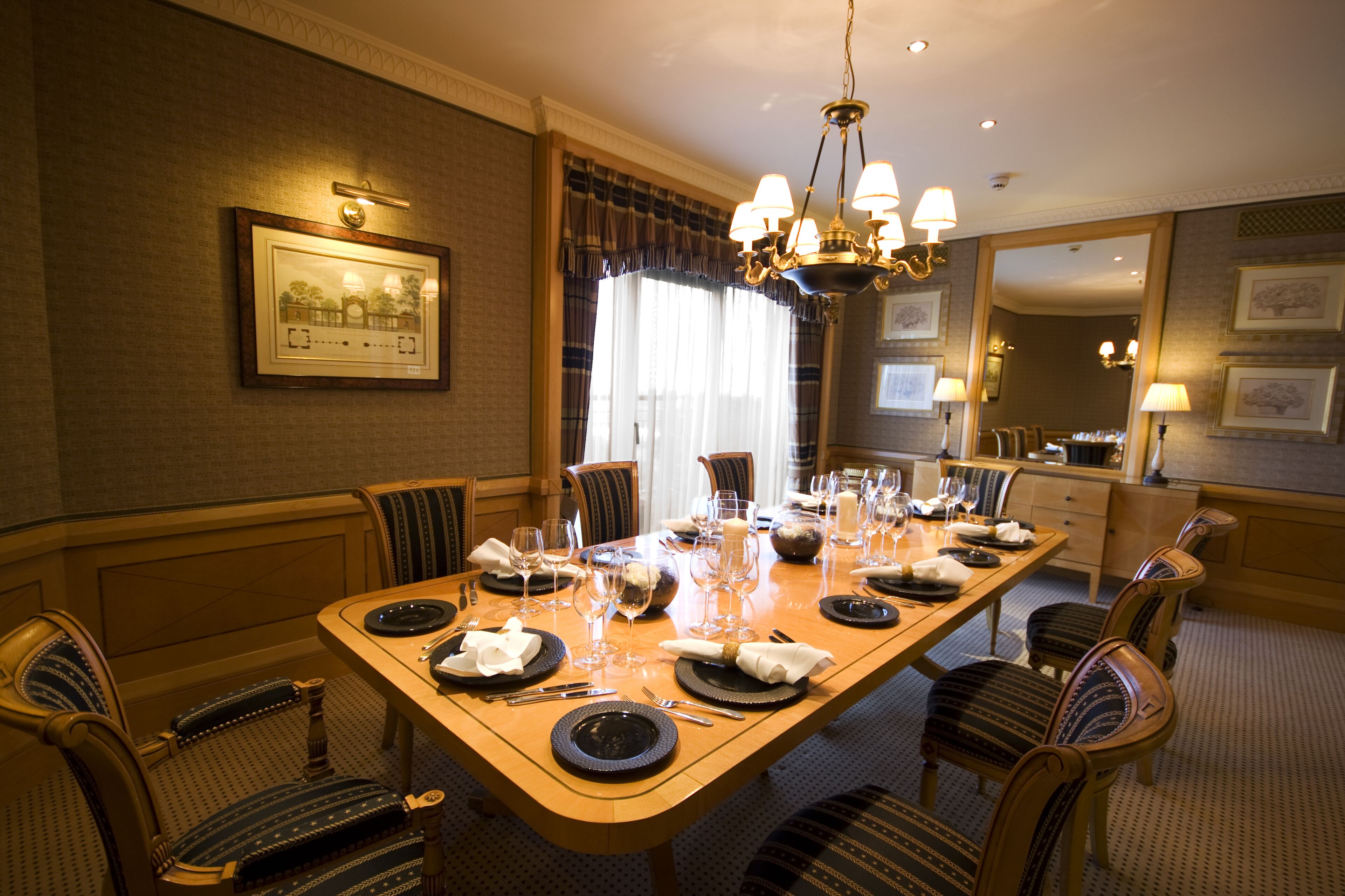 A dining area with a long table set for a meal, surrounded by upholstered chairs.