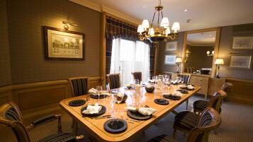 A dining area with a long table set for a meal, surrounded by upholstered chairs.